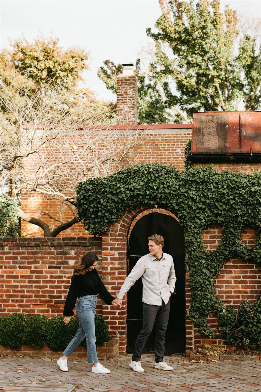 couple walking pose greenery and brick background