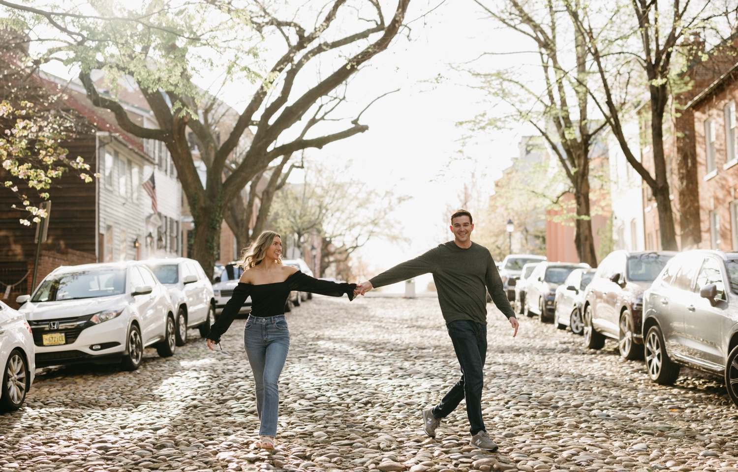 couple holding hands smiling cobblestone street