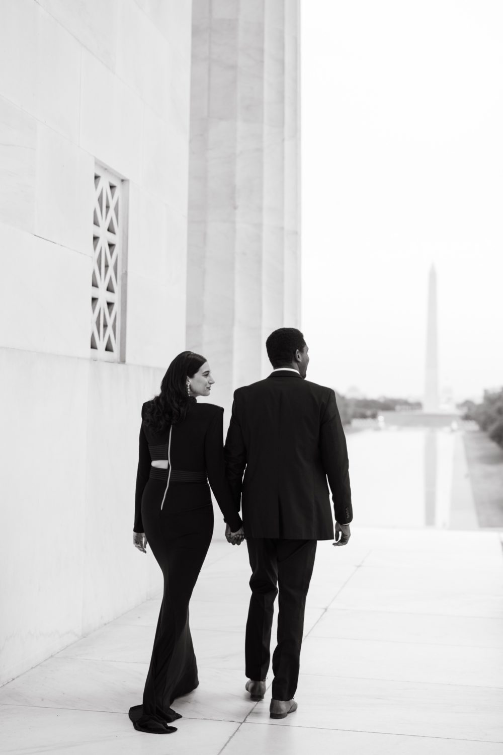 couple holding hands walking black and white