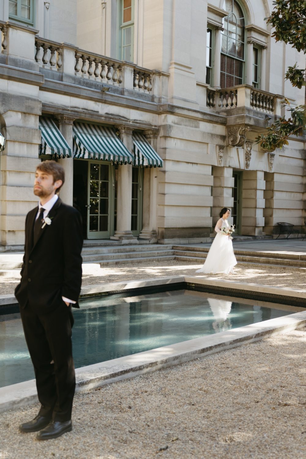 courtyard bride and groom first look black tux wedding dress