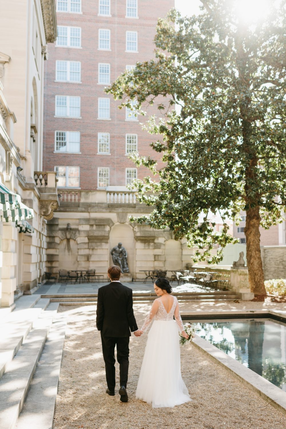 bride and groom holding hands walking courtyard