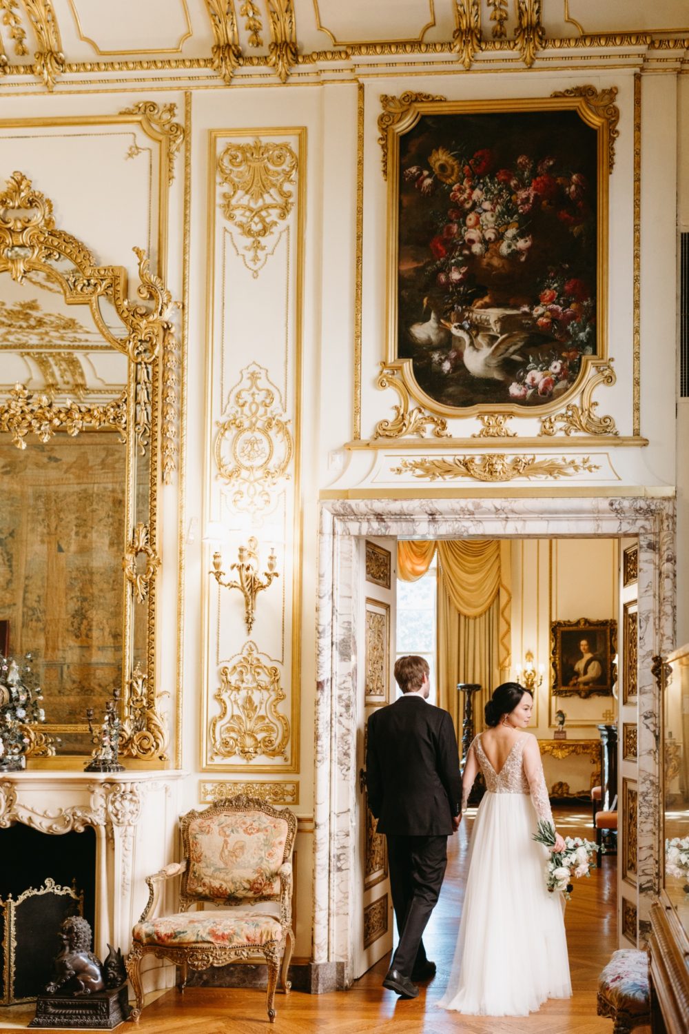 bride and groom holding hands walking golden room