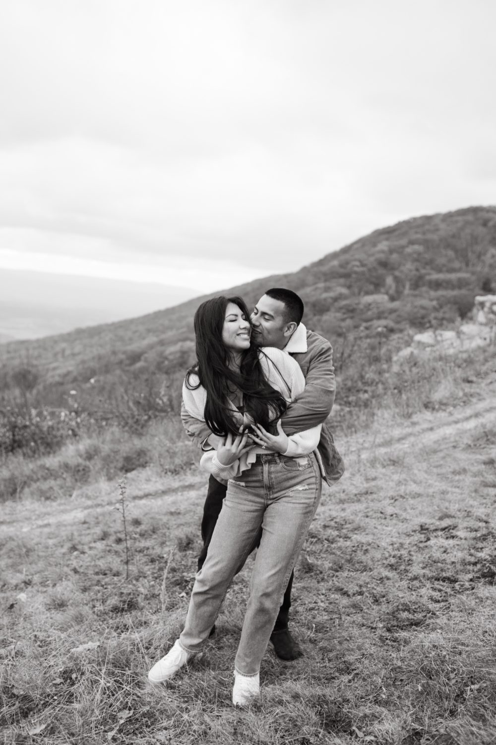 fiance hugging bride to be from behind black and white fall portrait
