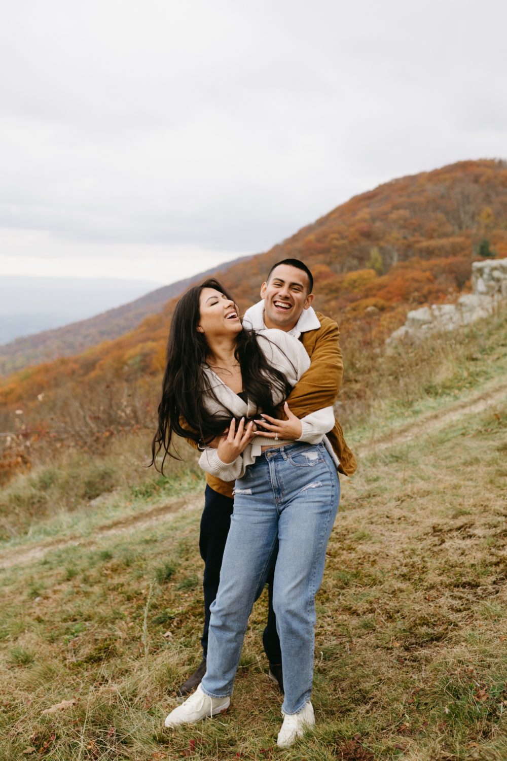 fall Shenandoah adventure engagement fiance hugging bride to be from behind mountainside setting