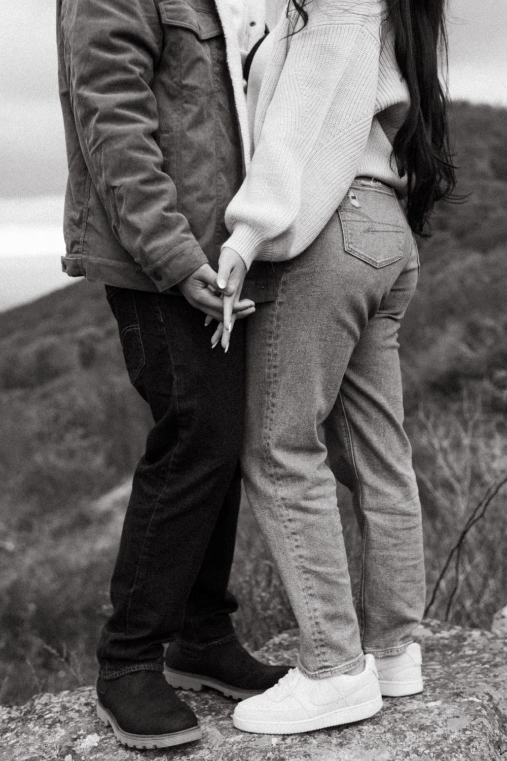 couple holding hands on mountainside black and white photo air jordans