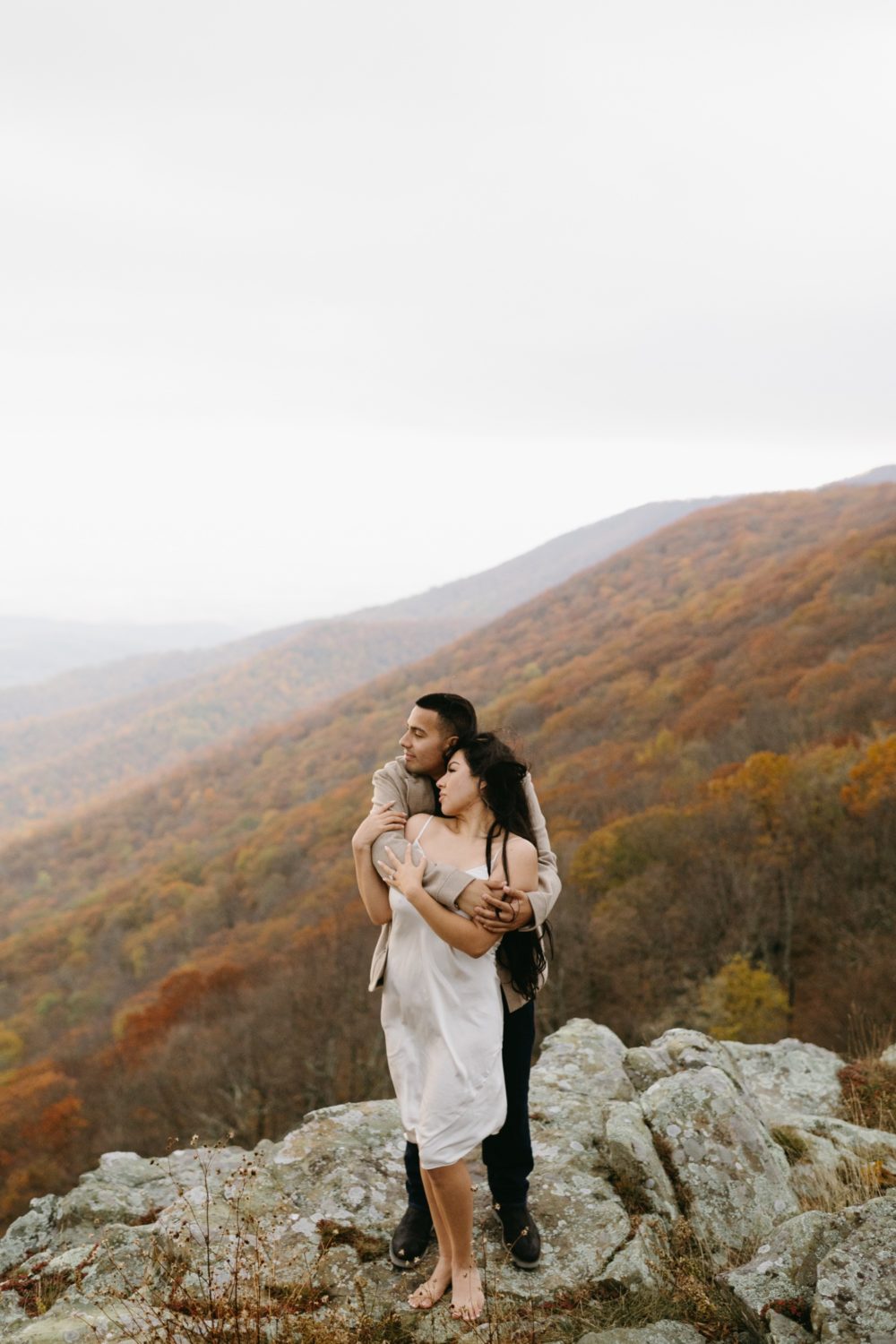 bride and groom to be on mountain overlook surrounded by fall foliage 