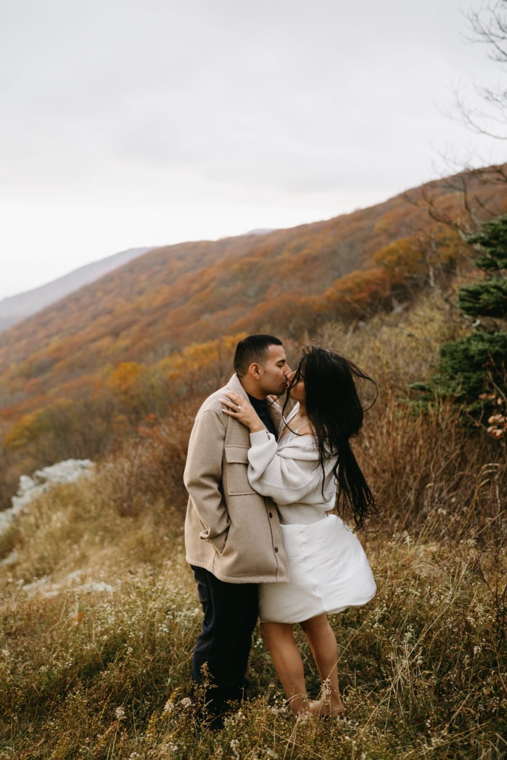 fall Shenandoah adventure engagement bride and groom kissing white silk dress oversized flannel jacket