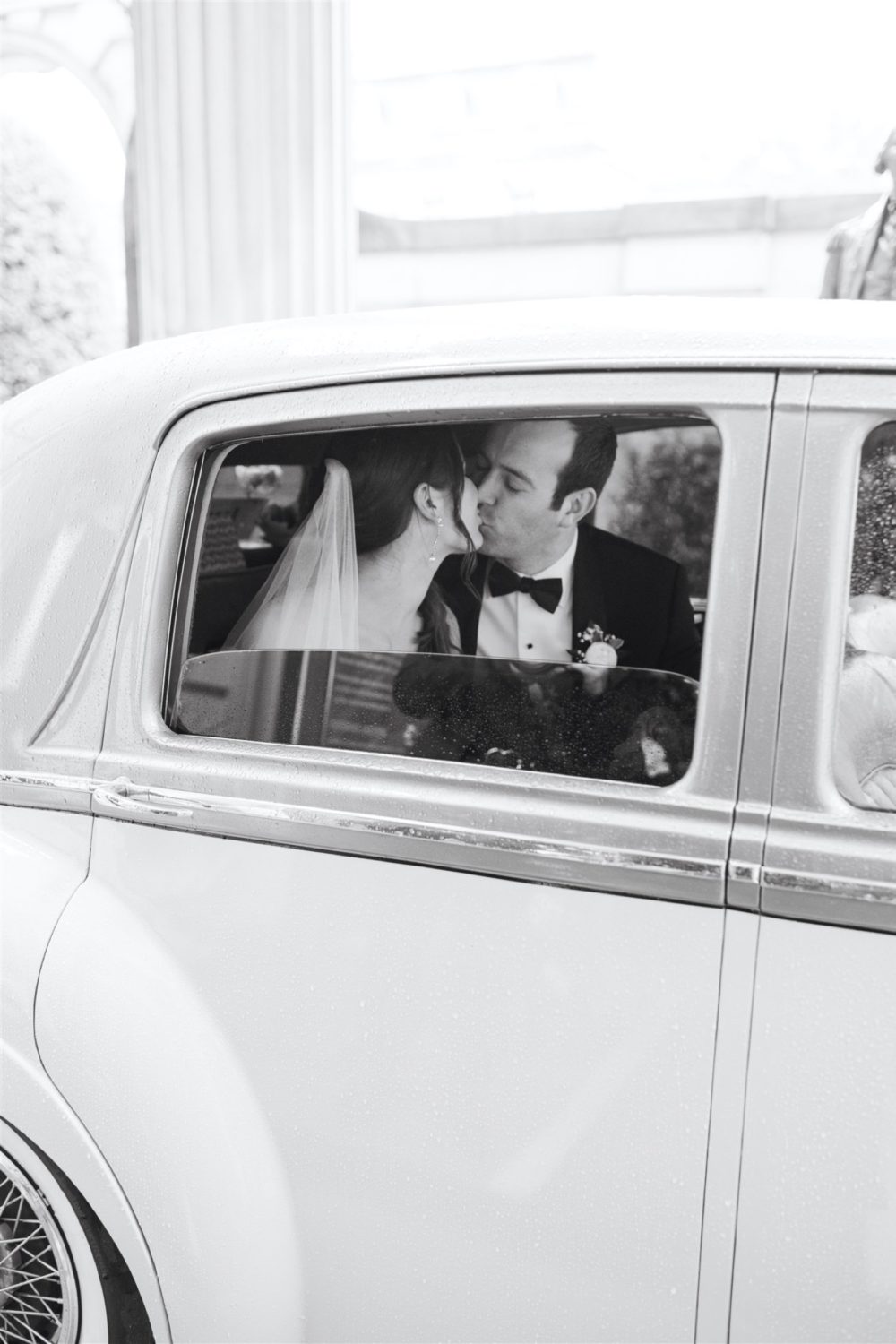 black and white bride and groom kissing vintage car