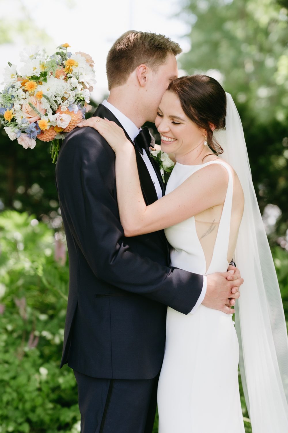 bride and groom hugging and smiling floral bouquet