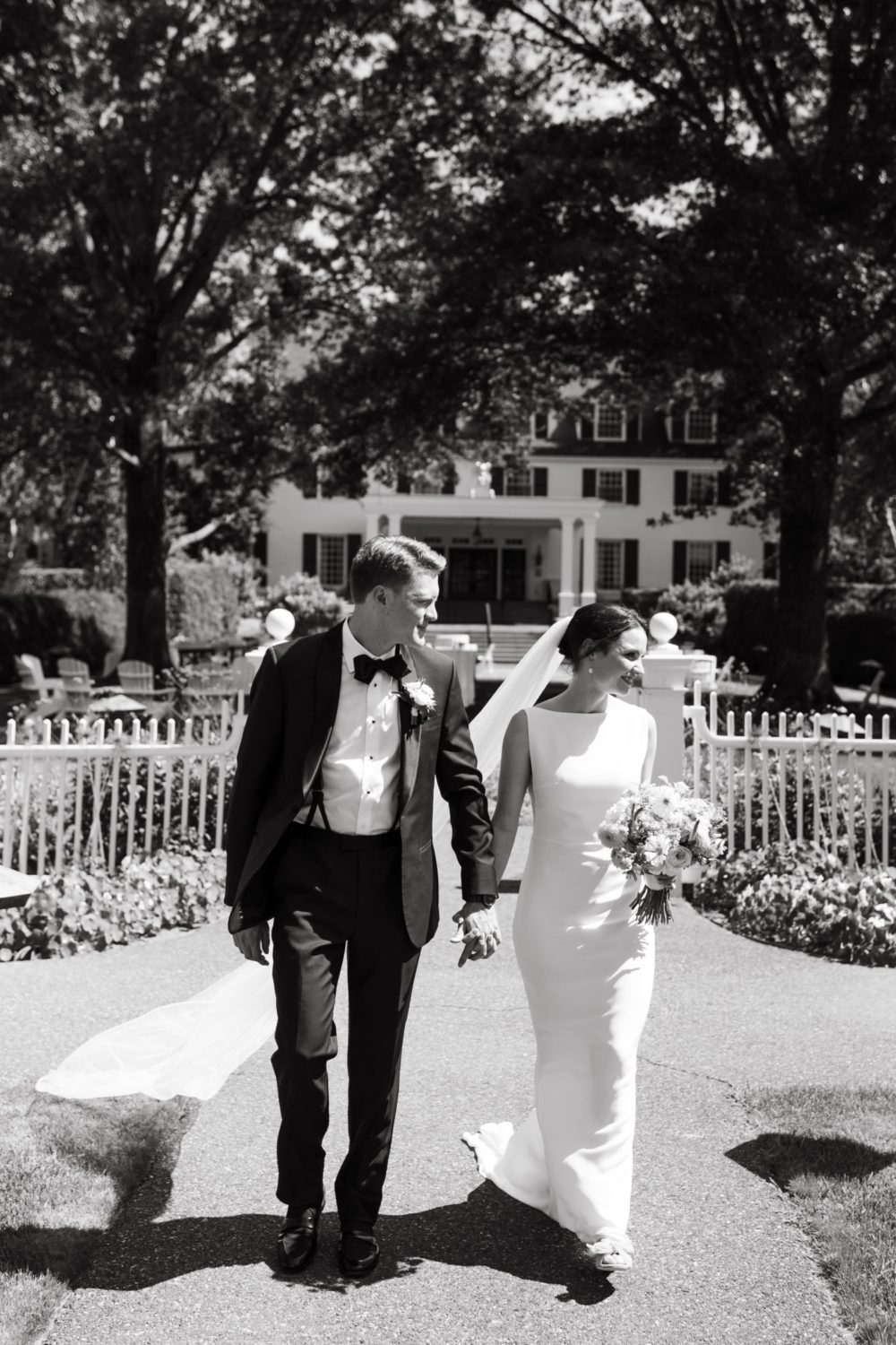 black and white portrait bride and groom holding hands walking