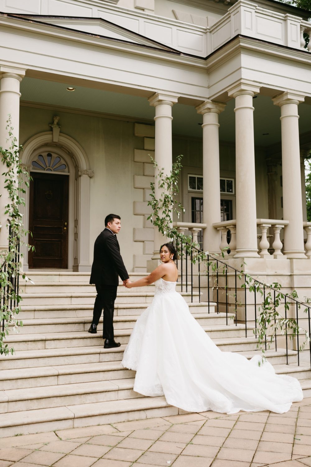 portrait bride and groom holding hands walking stairs venue