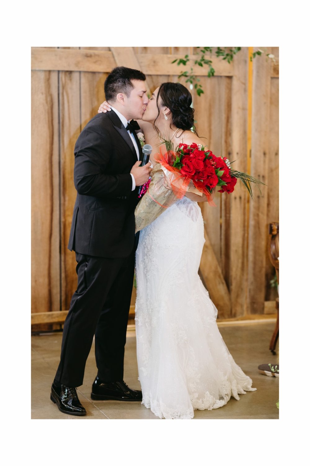 bride and groom kissing hugging holding roses