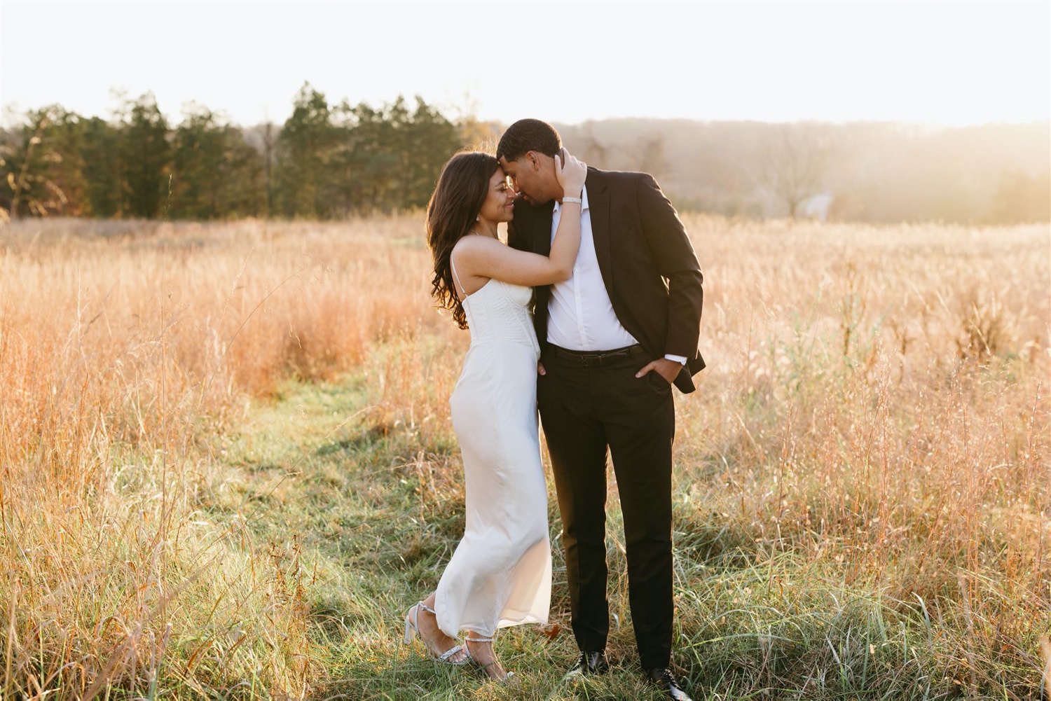 engagement photos bride and groom holding close golden field