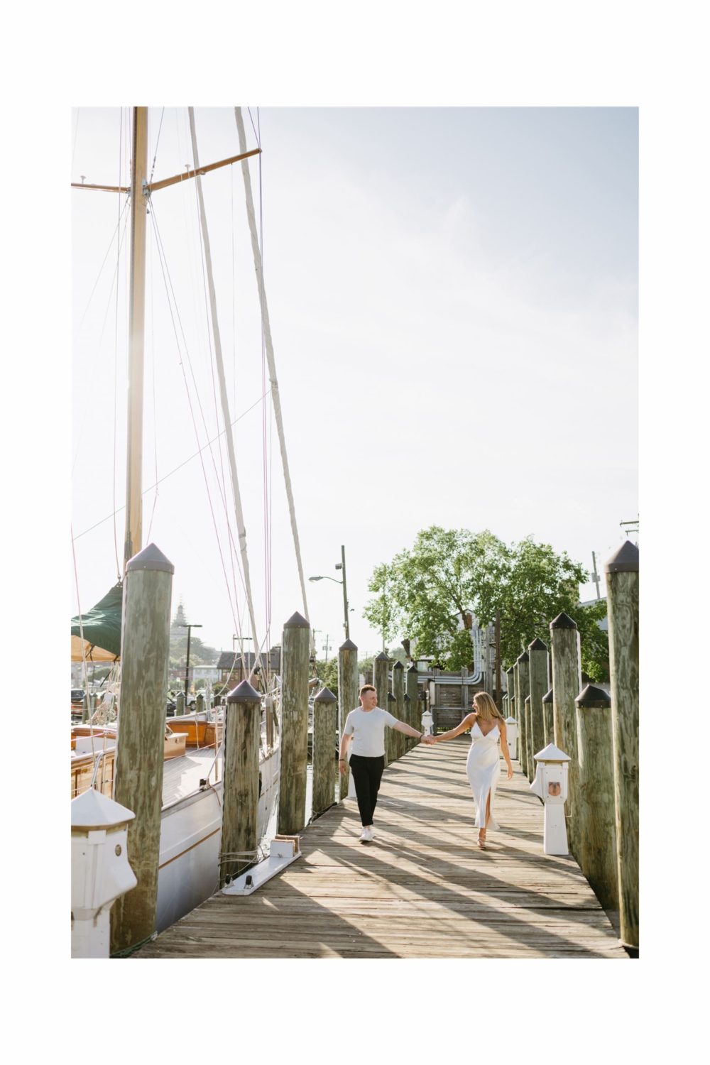 engaged couple holding hands outstretched walking annapolis marina 