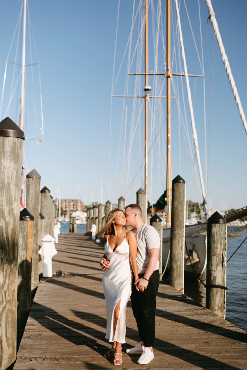 summer annapolis engagement guy kissing girl on cheek holding hands 