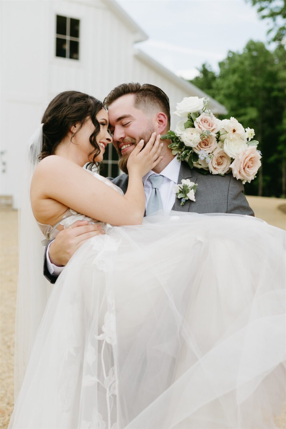 bride and groom smiling groom holding bride florals