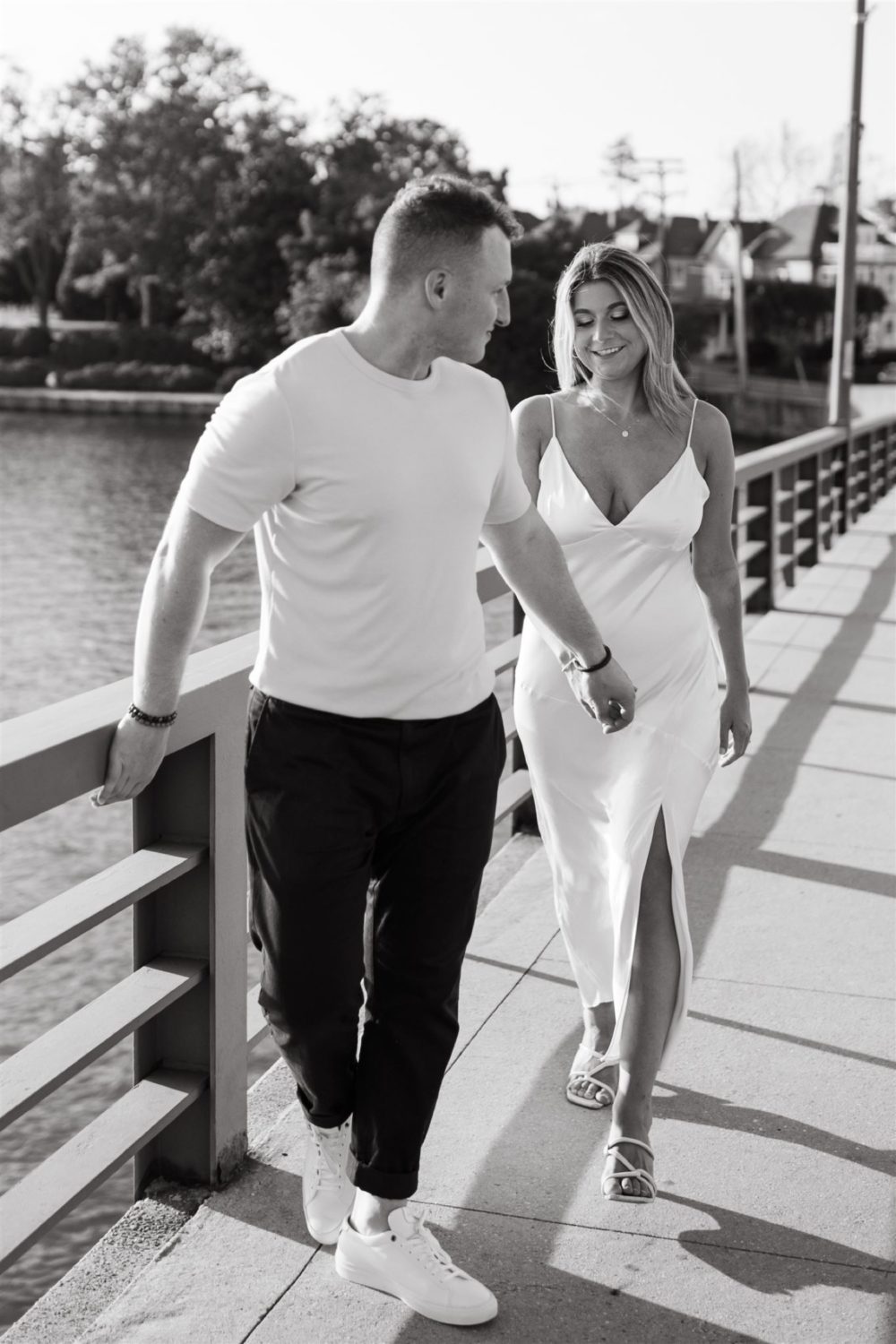 engaged couple walking bridge holding hands black and white
