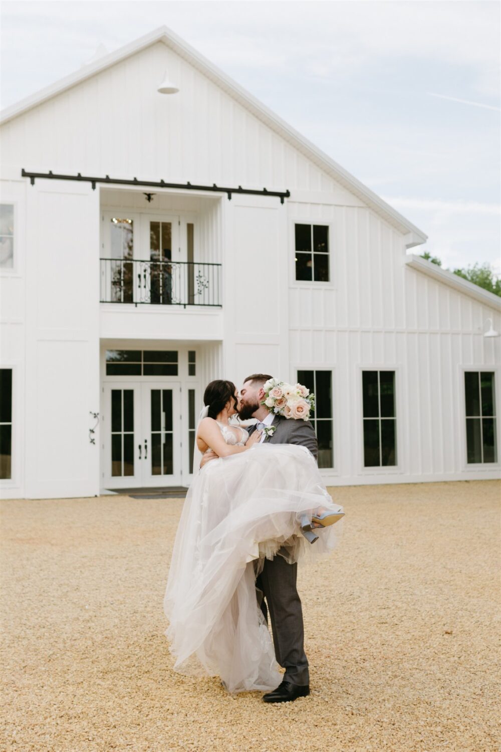 ivy rose barn bride and groom kissing groom holding bride florals