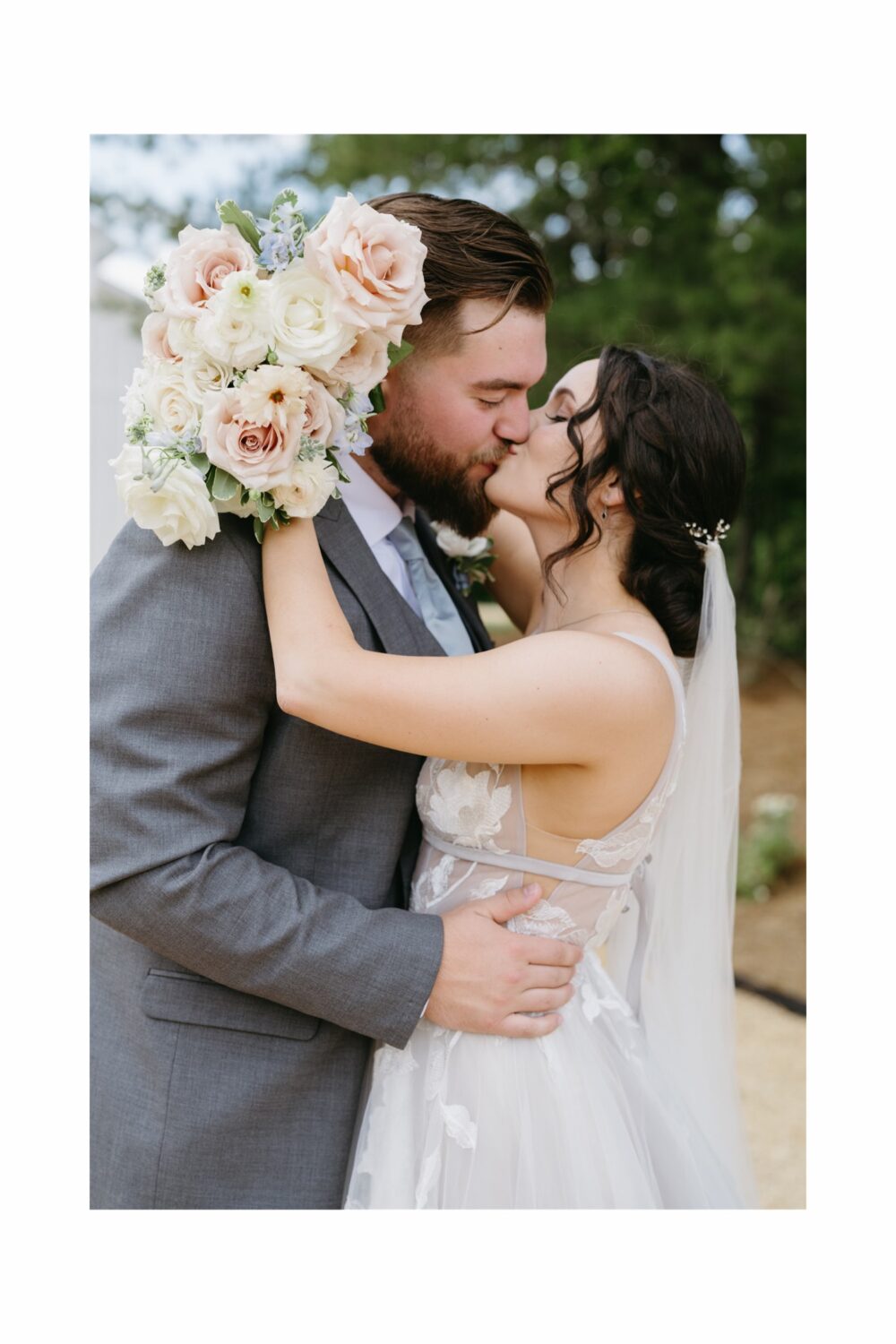 bride and groom kissing hugging wedding florals