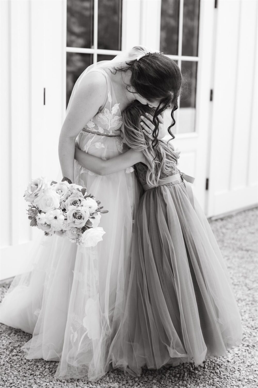 black and white portrait bride hugging flower girl florals