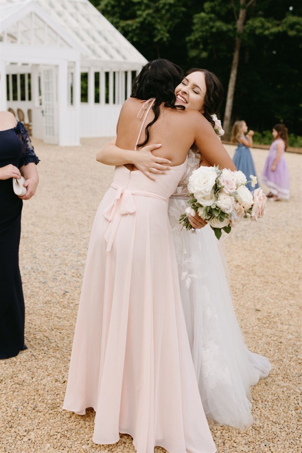 ivy rose barn bride hugging bridesmaid smiling florals