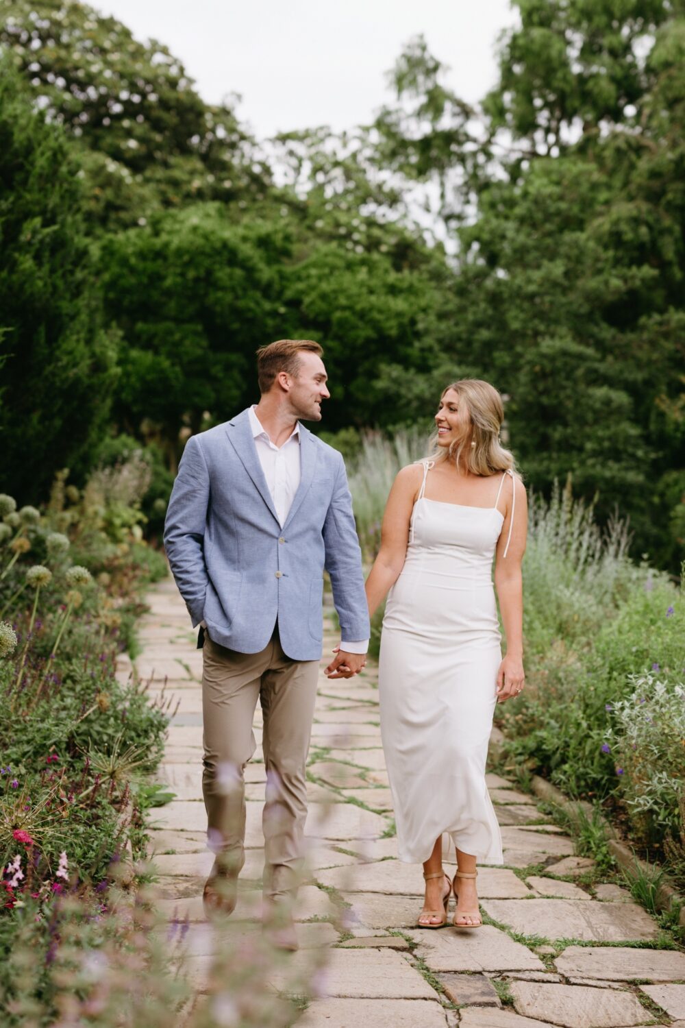 bride and groom to be walking along wildflower path National Cathedral Engagement Session