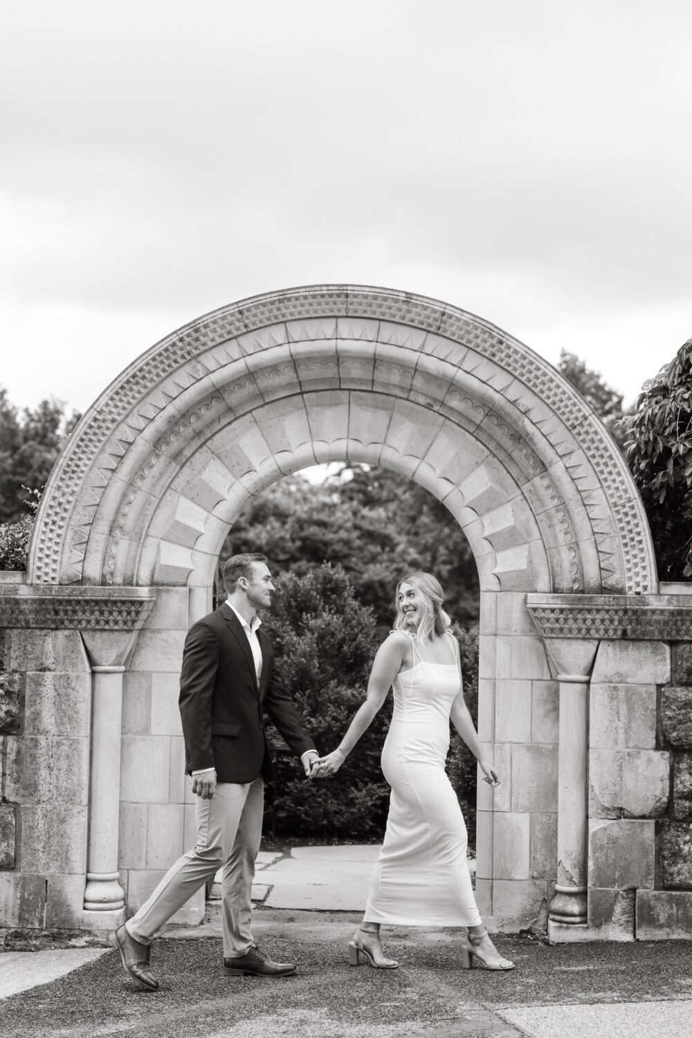national cathedral engagement session bride leading groom by hand black and white picture