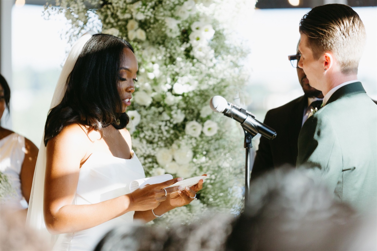 bride reading vows white ceremony florals