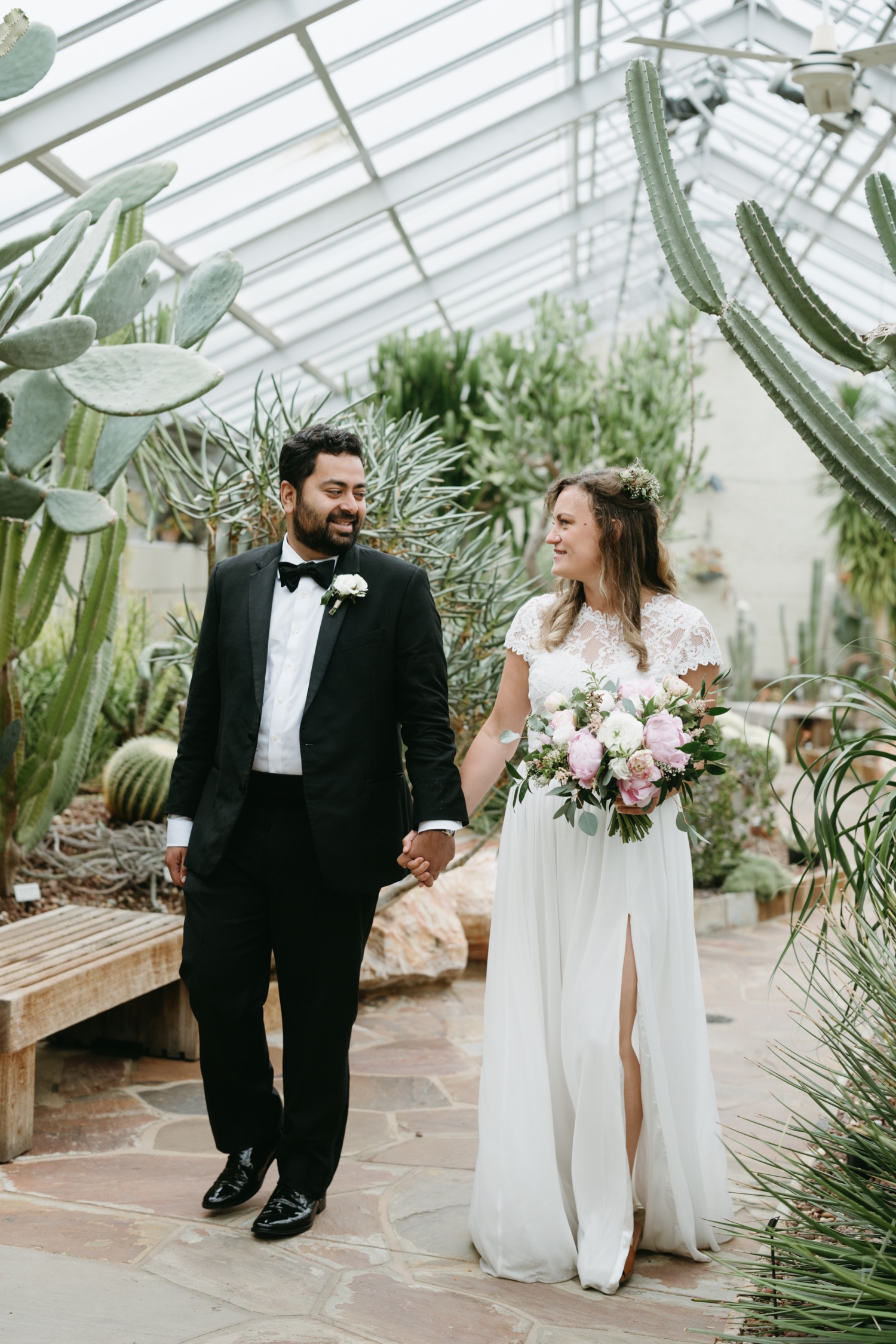 bride and groom walking through greenhouse pink and white florals