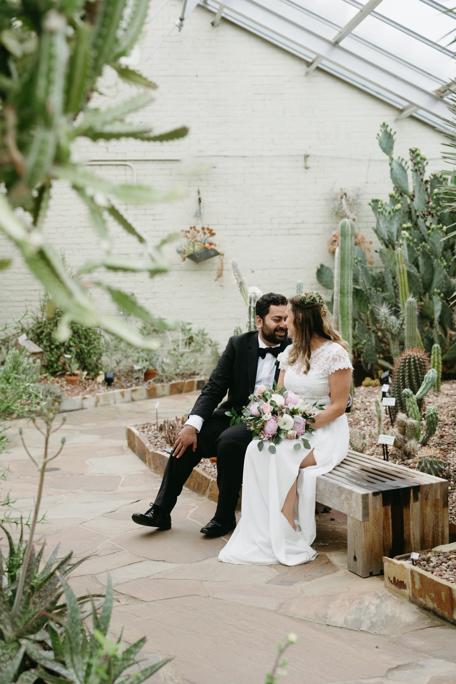 Rawlings Conservatory Baltimore Elopement bride and groom seated on bench looking into each others eyes surrounded by desert flora