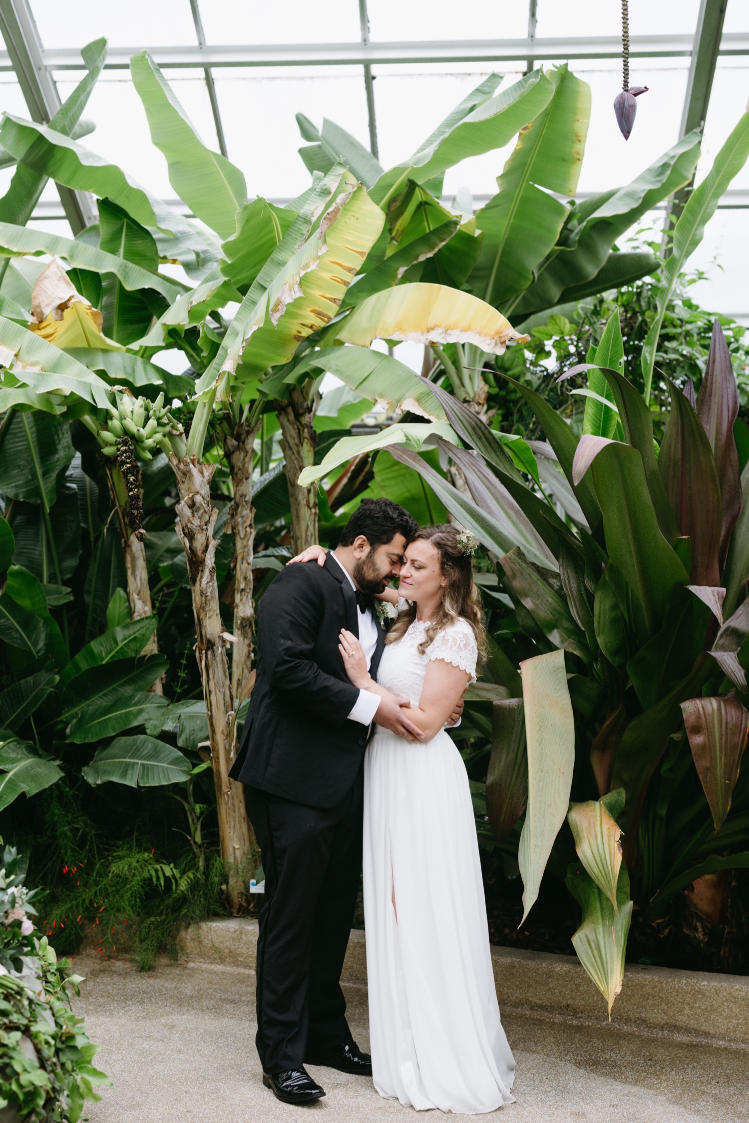 bride and groom hugging rawlings conservatory surrounded by greenhouse flora