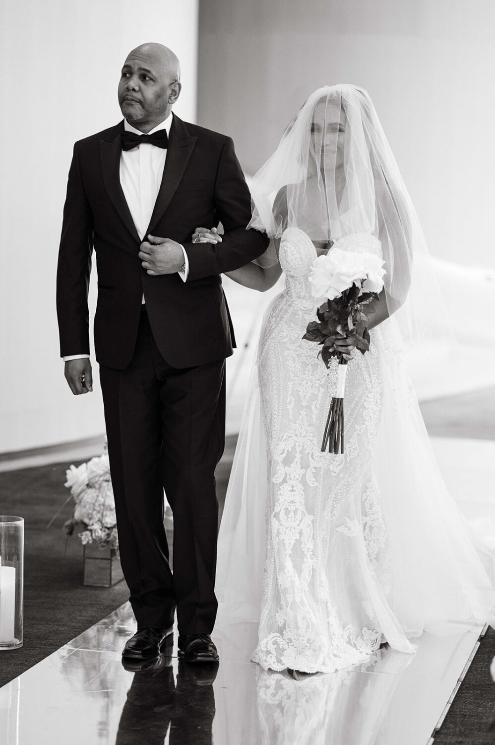 father escorting bride down the aisle black and white bride smiling with bridal veil