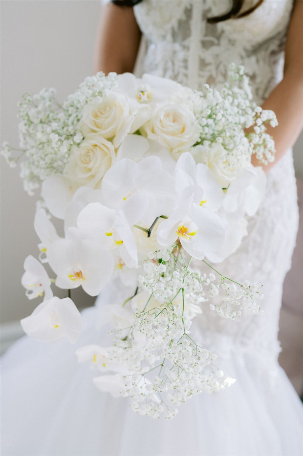 bride wedding bouquet white and cream color palette featuring orchids baby breath and orchids 