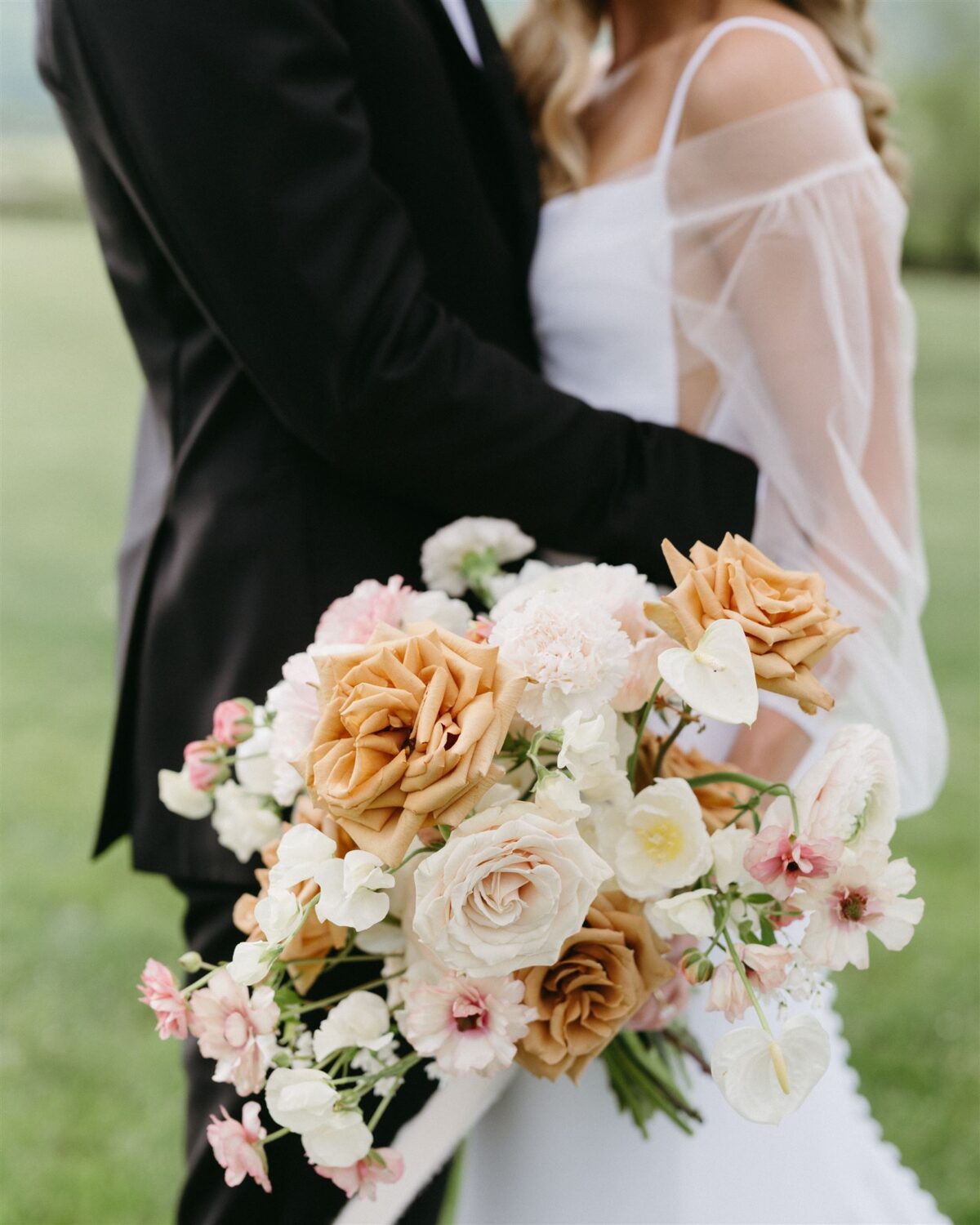 bride and groom kissing nude and cream colored roses
