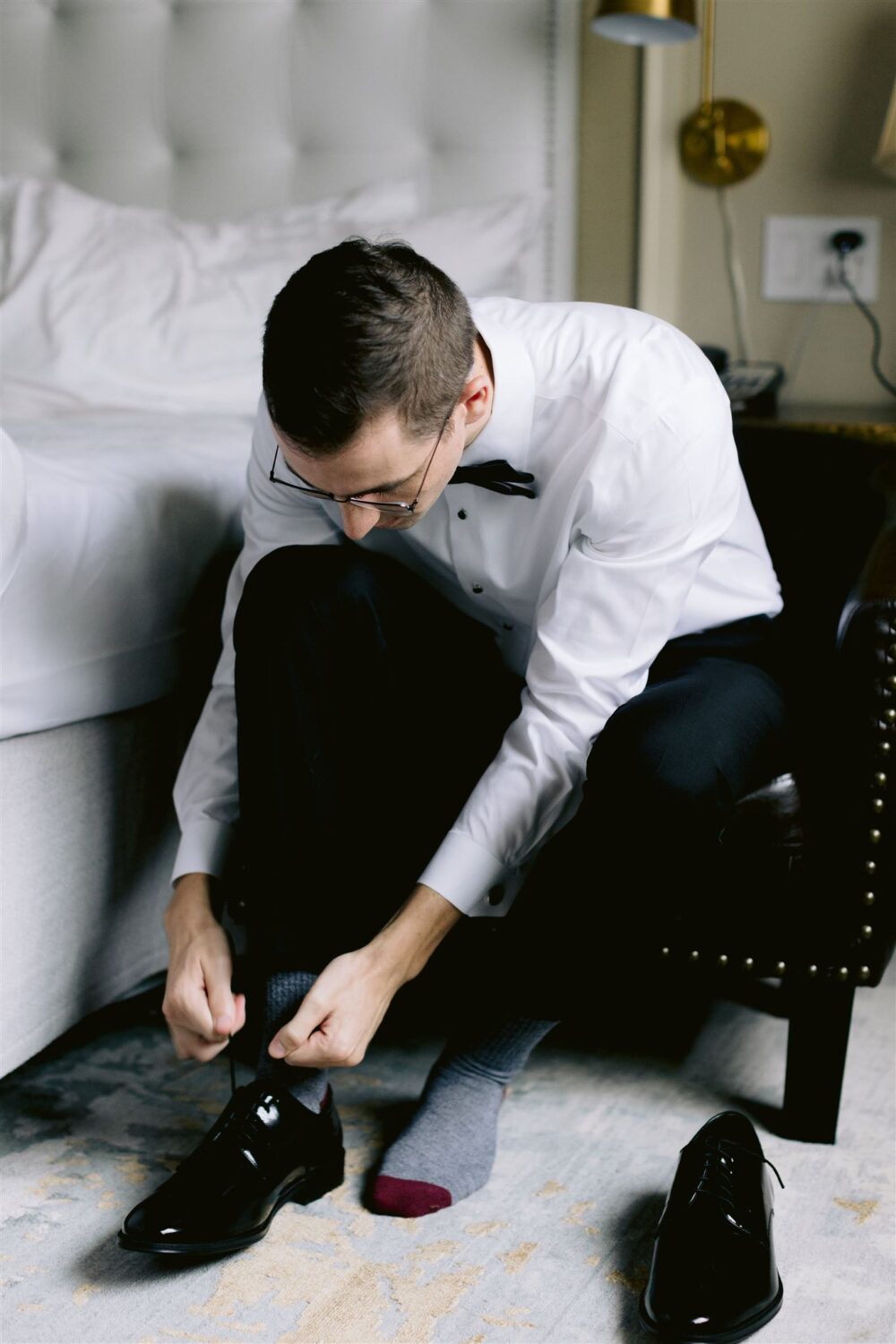 groom tying shoes getting ready photos modern wedding