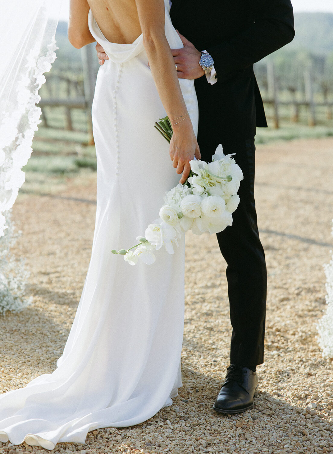 bride and groom kissing featuring florals bridal bouquet white peonies orchids hydrangeas 